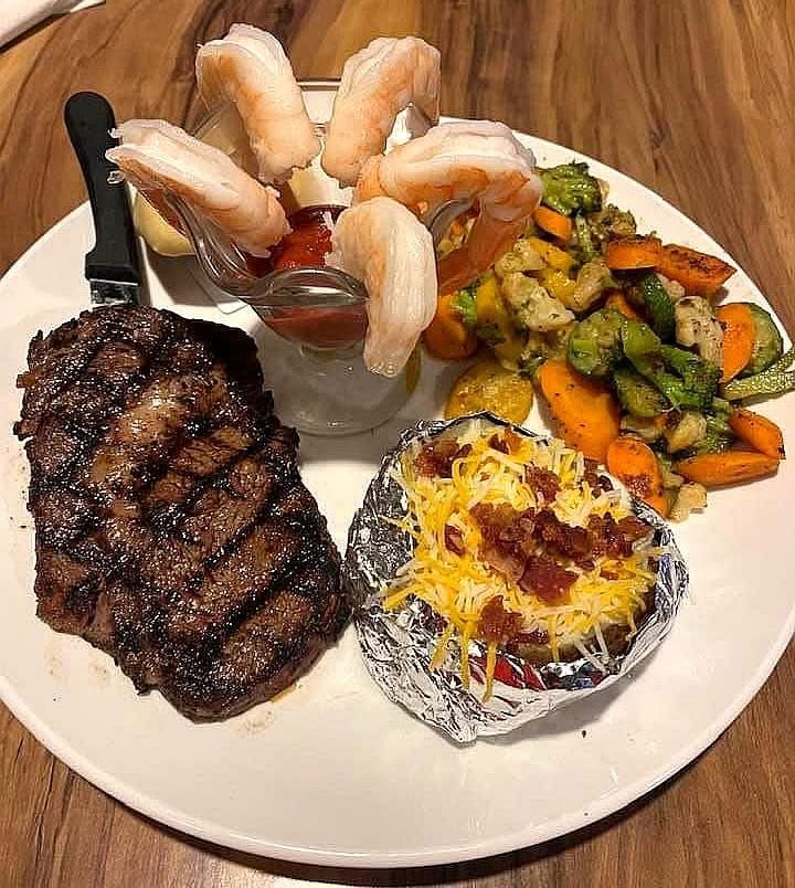Ribeye steak with shrimp cocktail and roasted vegetables