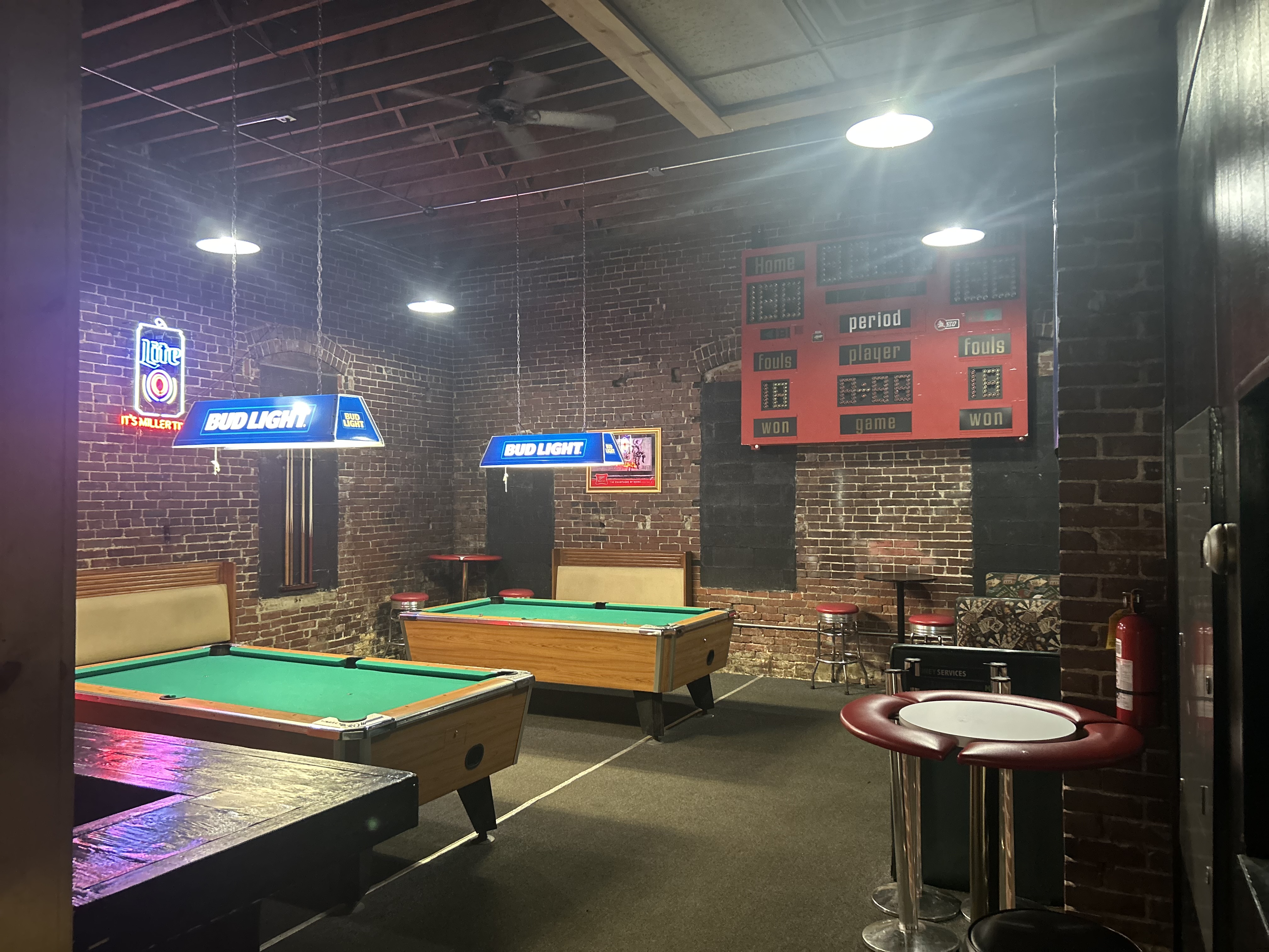 Pool and game room at The Vault — two pool tables, brick walls, neon beer signs