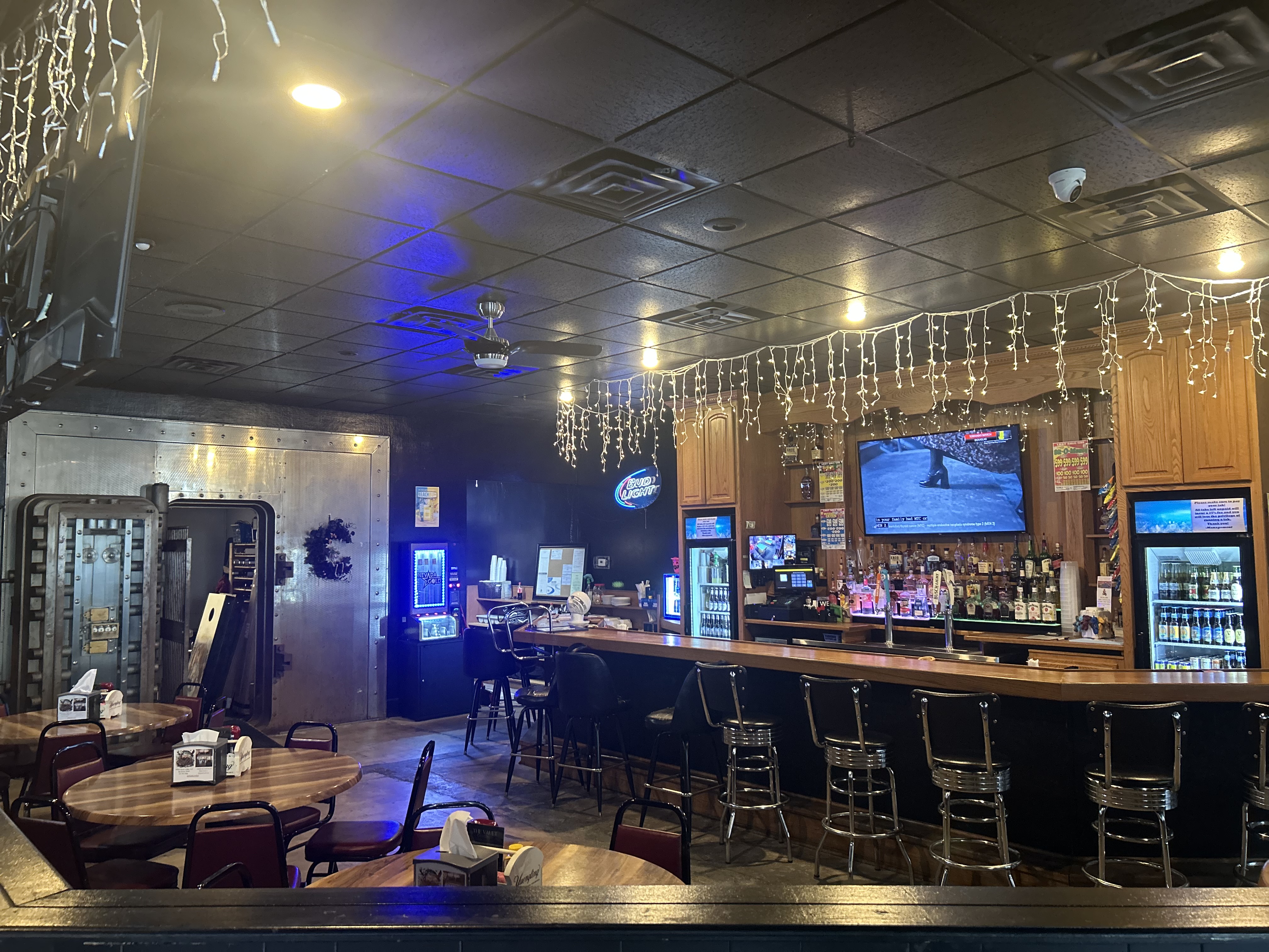 The vault door and bar area — blue mood lighting, string lights, TVs