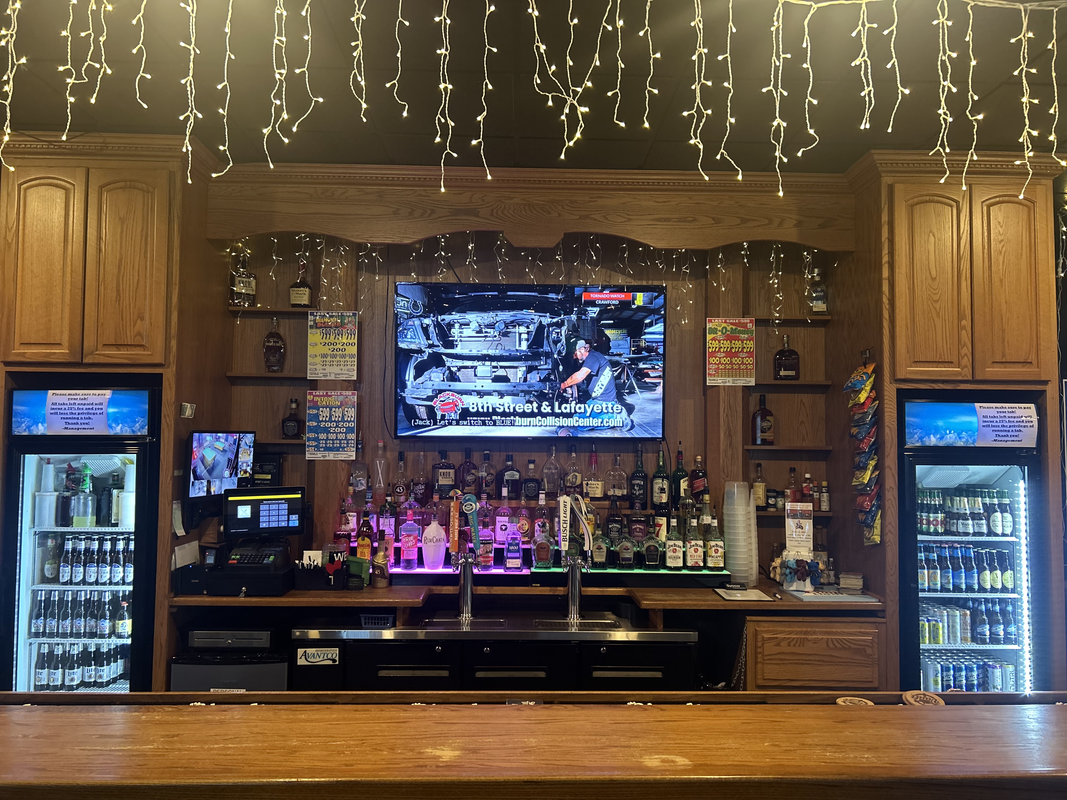 The Vault back bar — full liquor shelf, TV, string lights, beer fridges on both sides