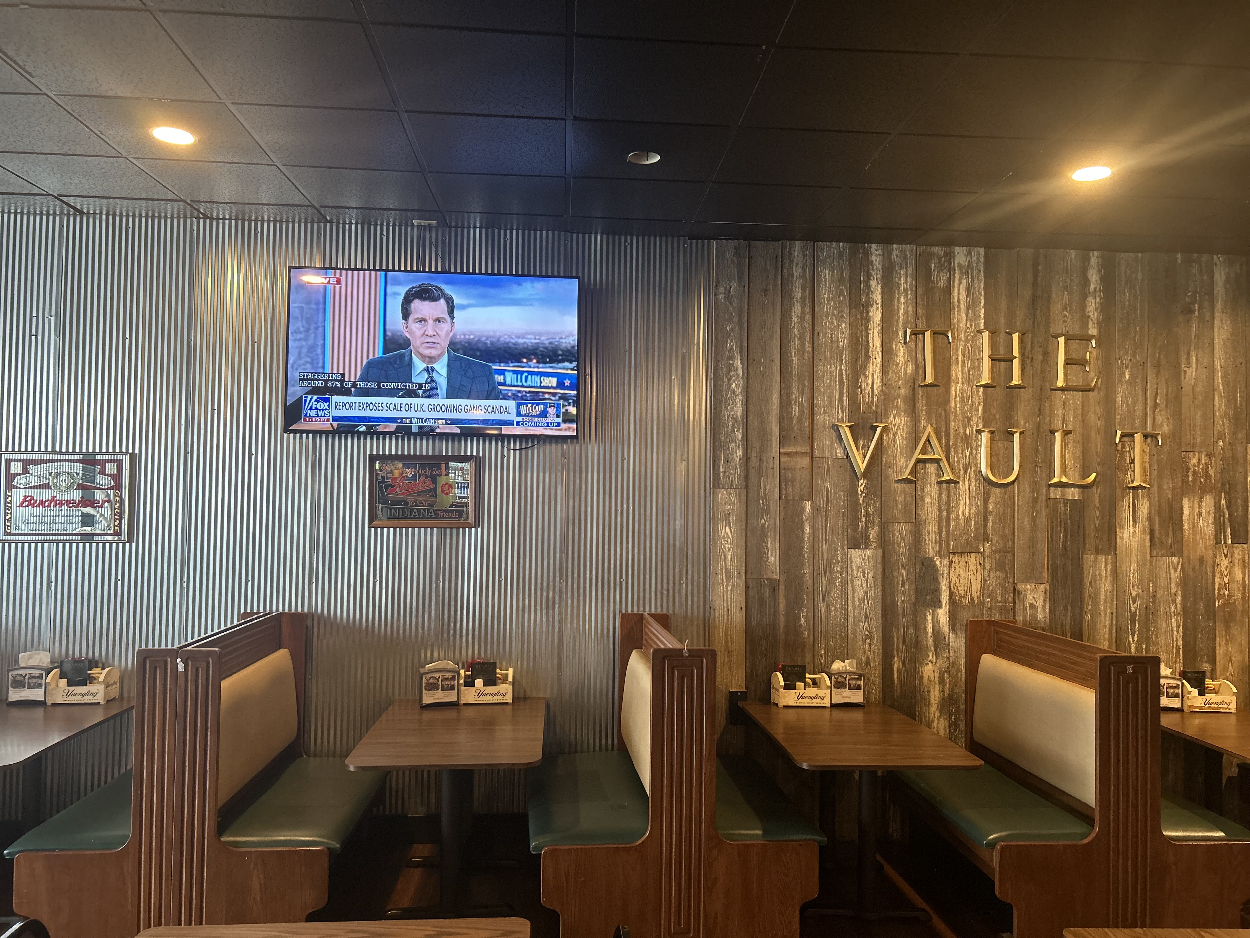 THE VAULT gold letters on wood wall with green booth seating in the dining room