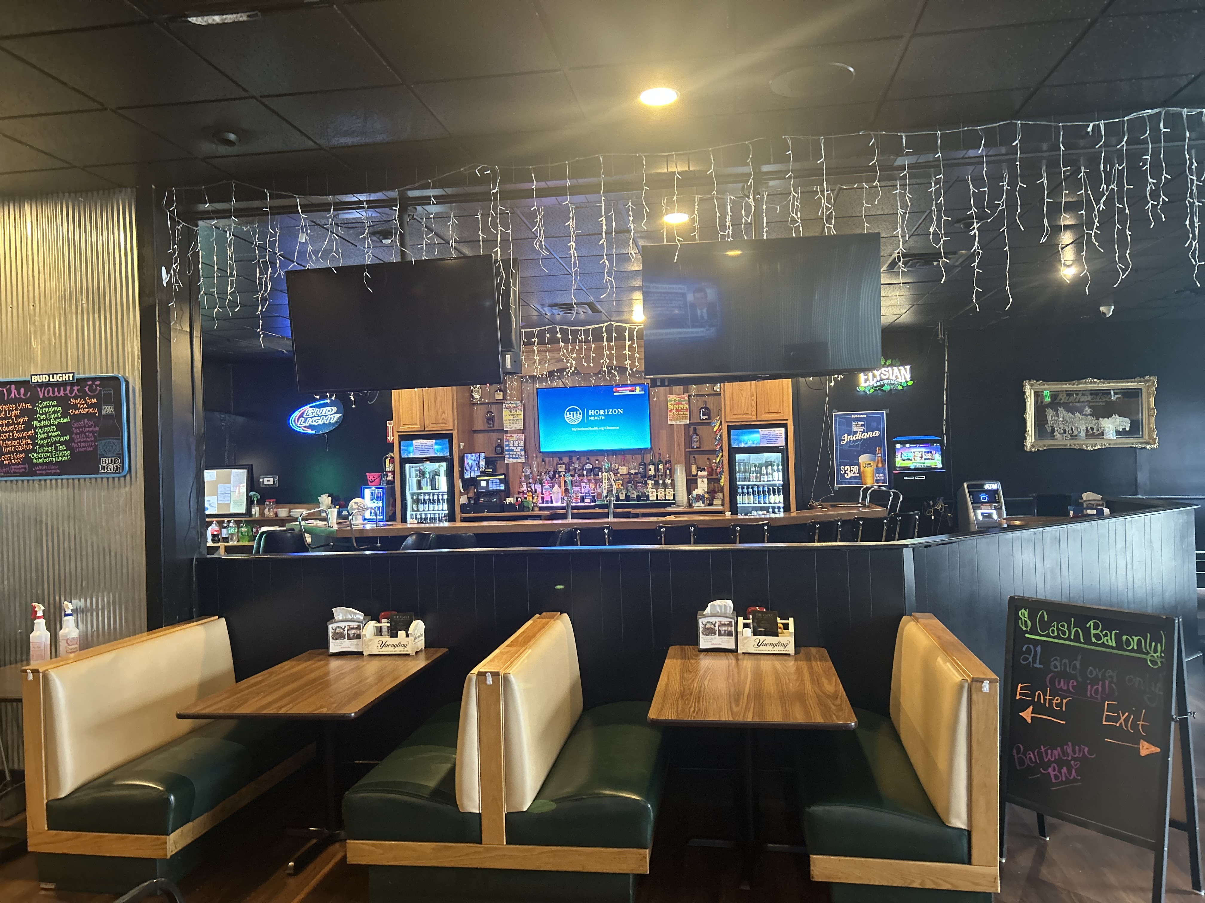 Wide view of The Vault — dining booths in foreground with the full bar visible behind
